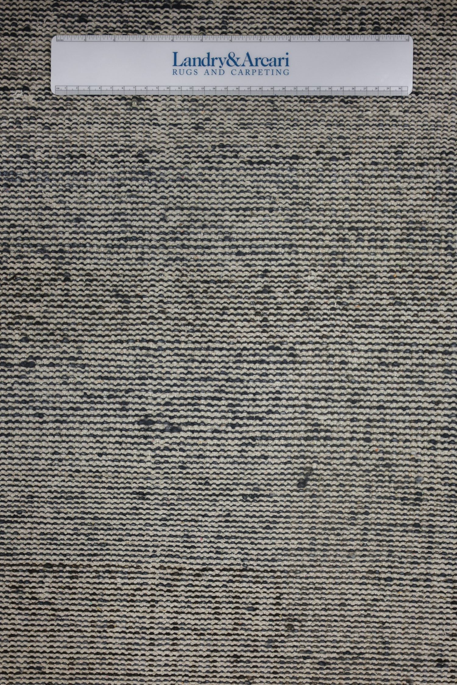 Handwoven rug detail: neutral beige and charcoal gray tones in an abstract plaid pattern.
