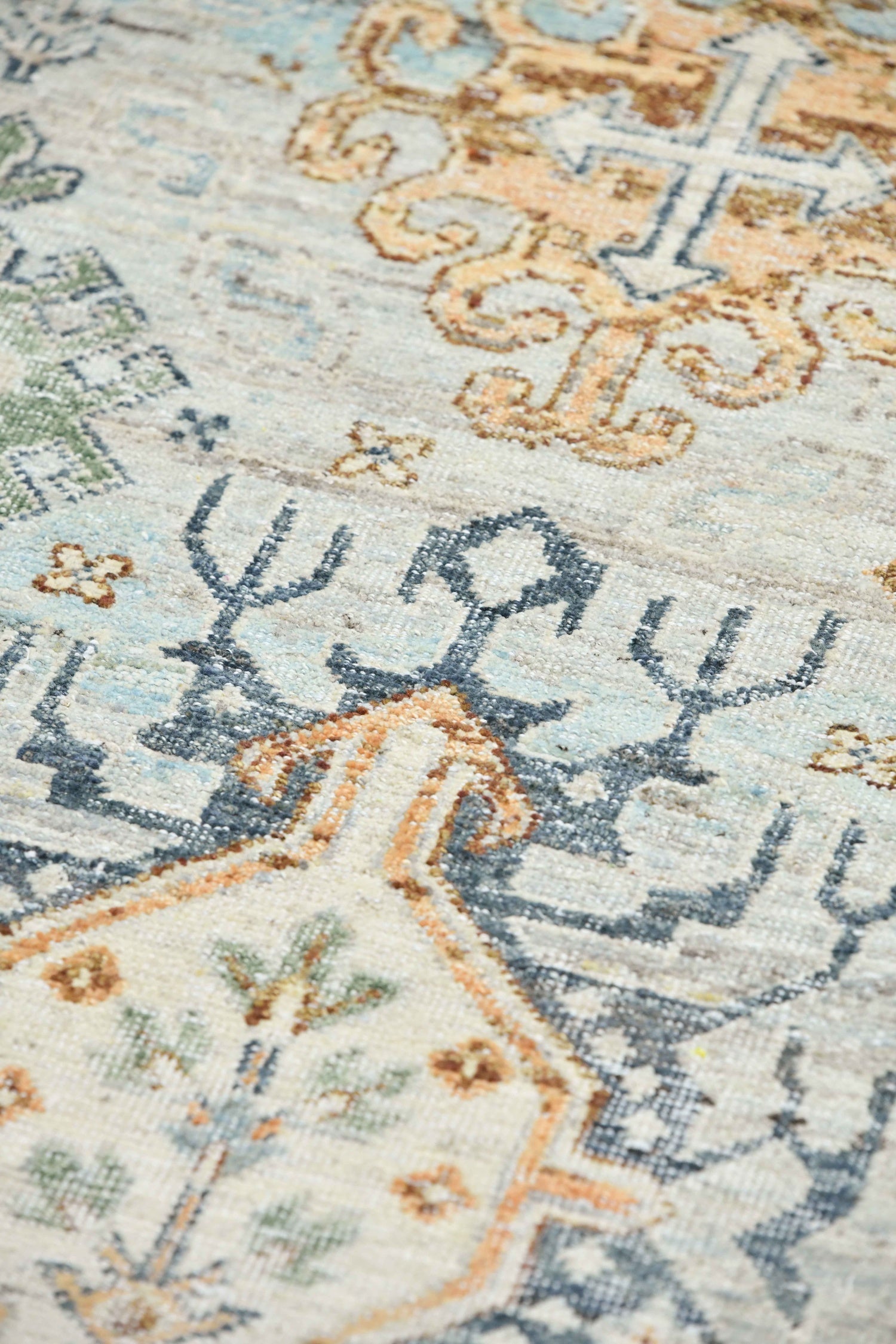 Handwoven rug detail:  Neutral-toned pattern with blue, orange, and green accents.
