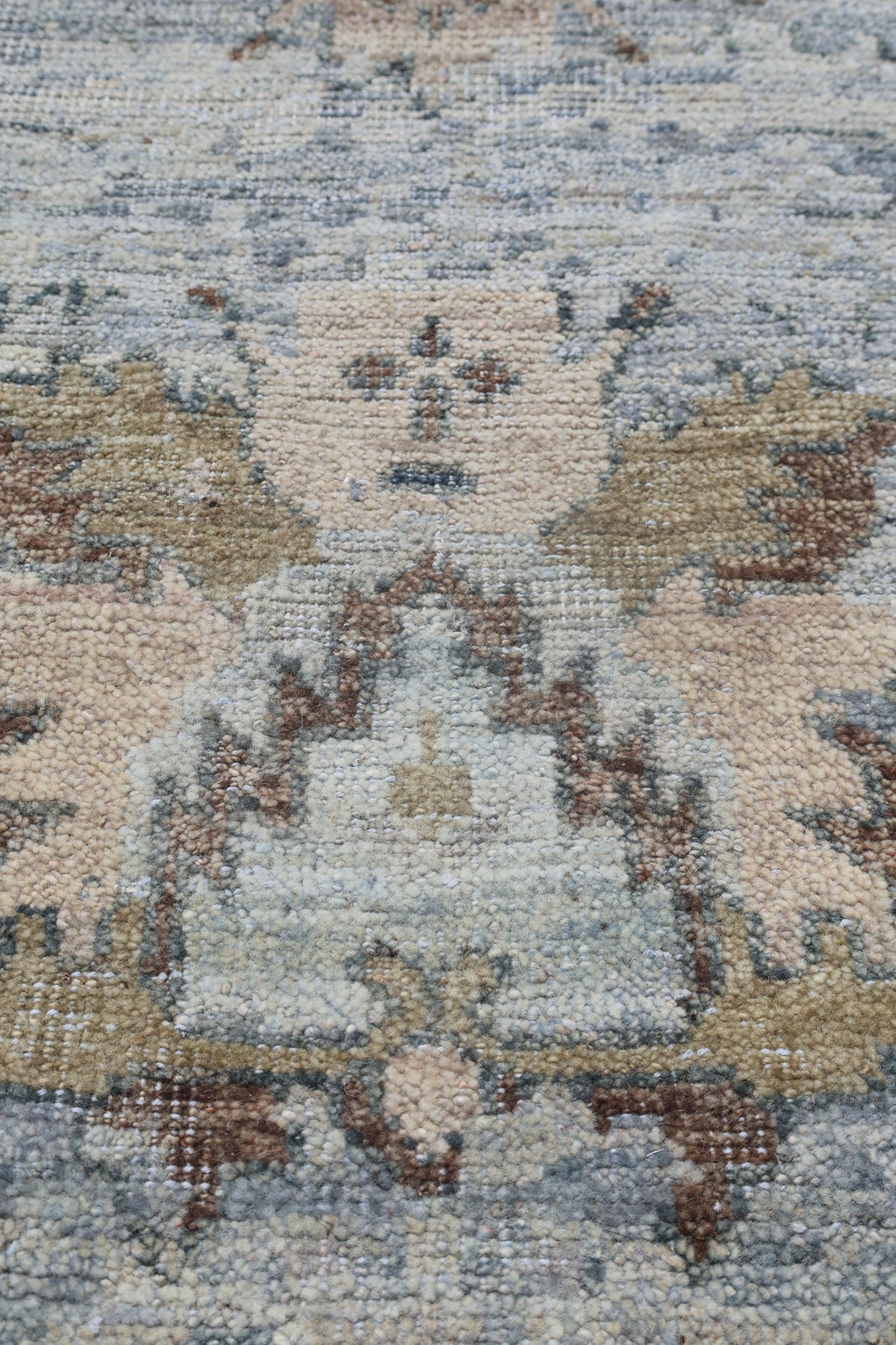 Close-up of a handwoven rug with a muted blue, beige, and brown pattern.
