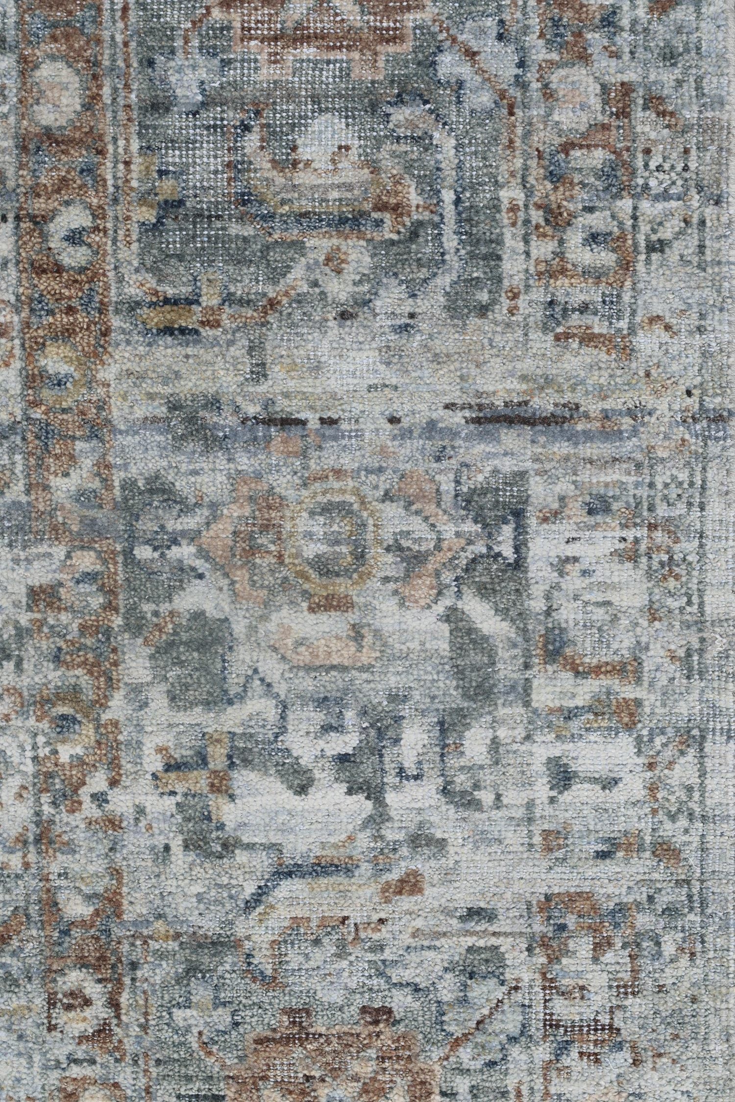 Handwoven rug detail, showcasing a transitional Serapi design in muted blues, beige, and browns.
