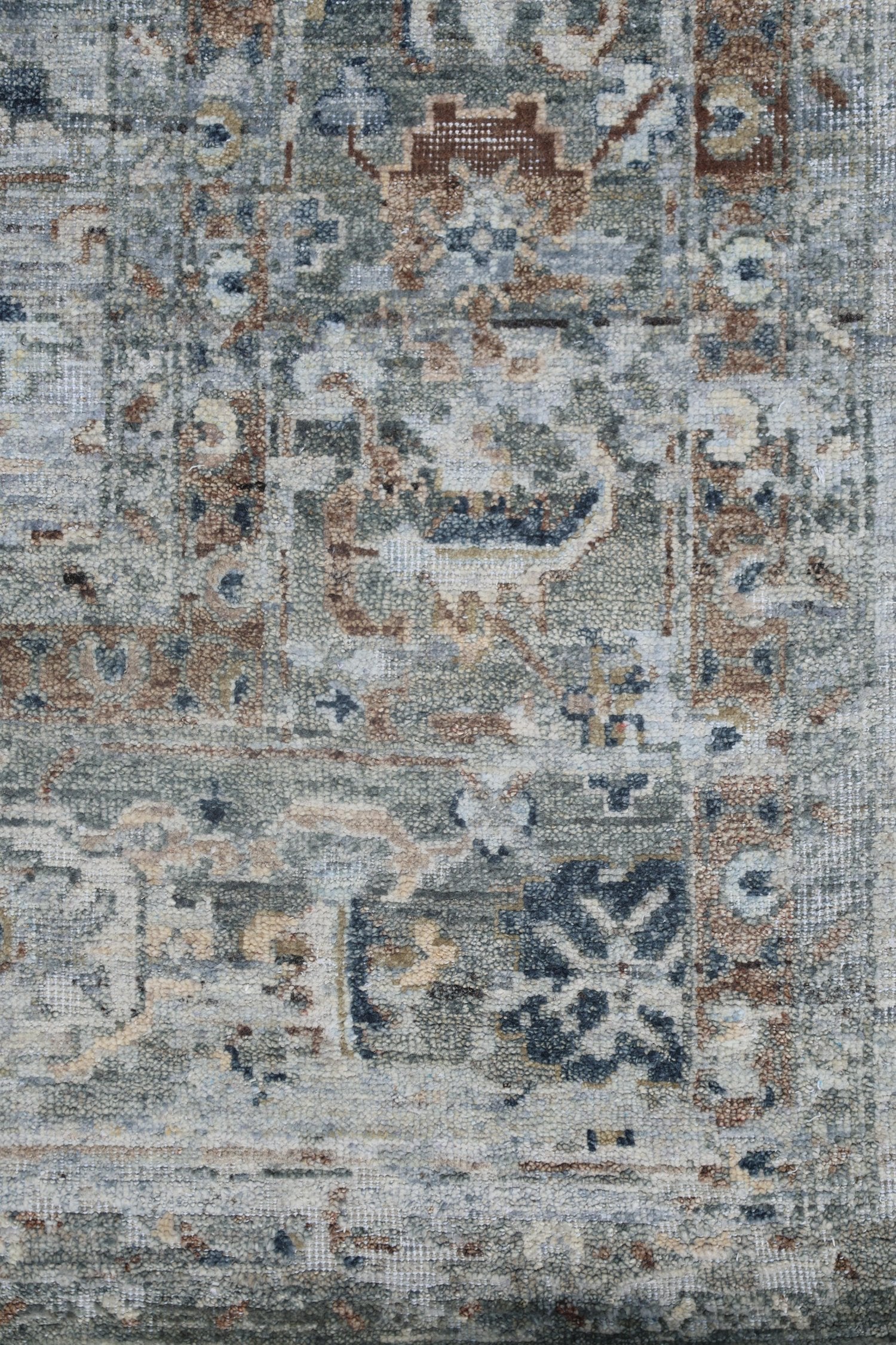 Handwoven rug detail, showcasing a transitional design in muted blues, browns, and beige tones.
