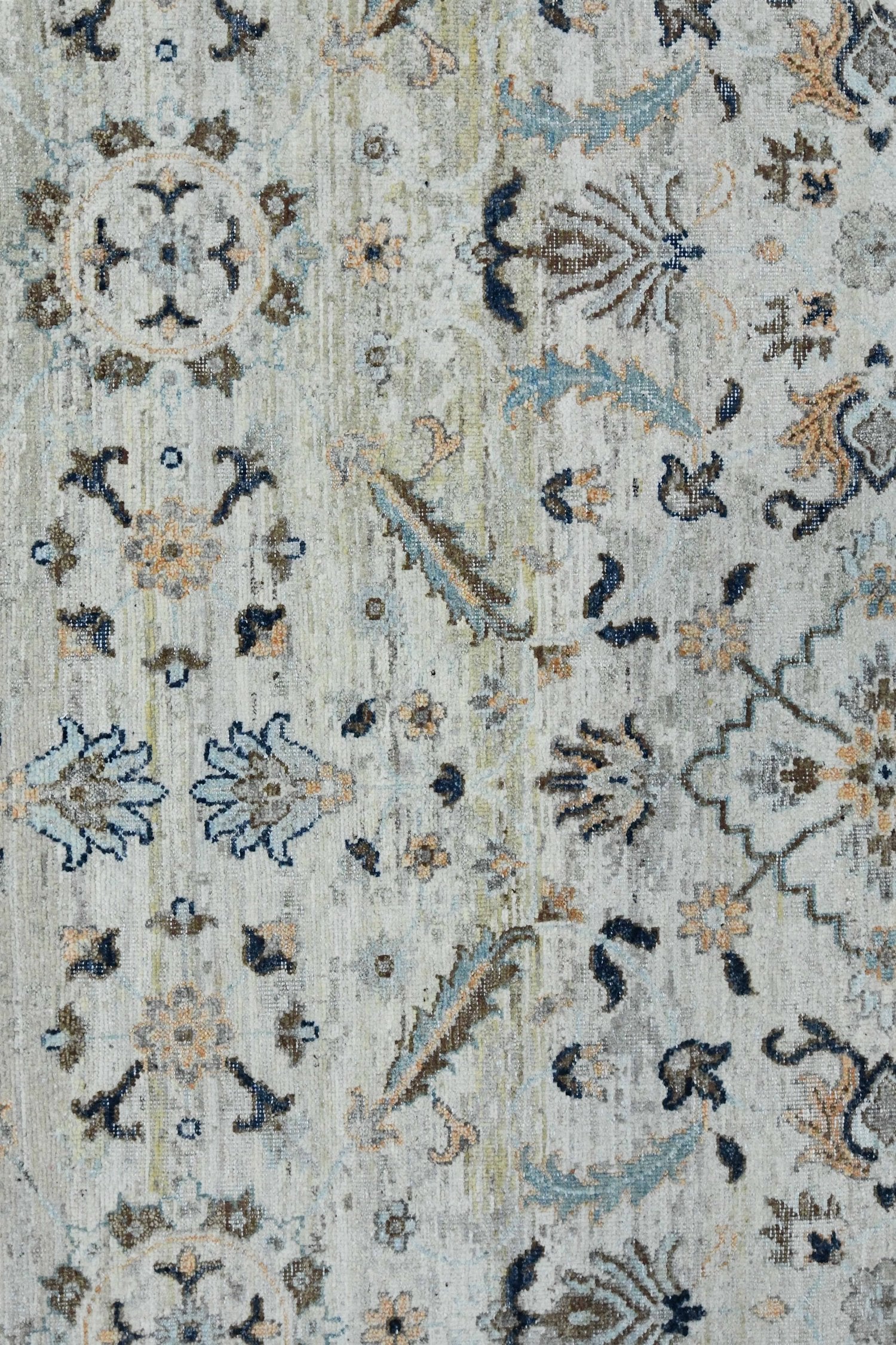 Handwoven rug detail: Beige base with intricate blue, brown, and cream floral pattern.
