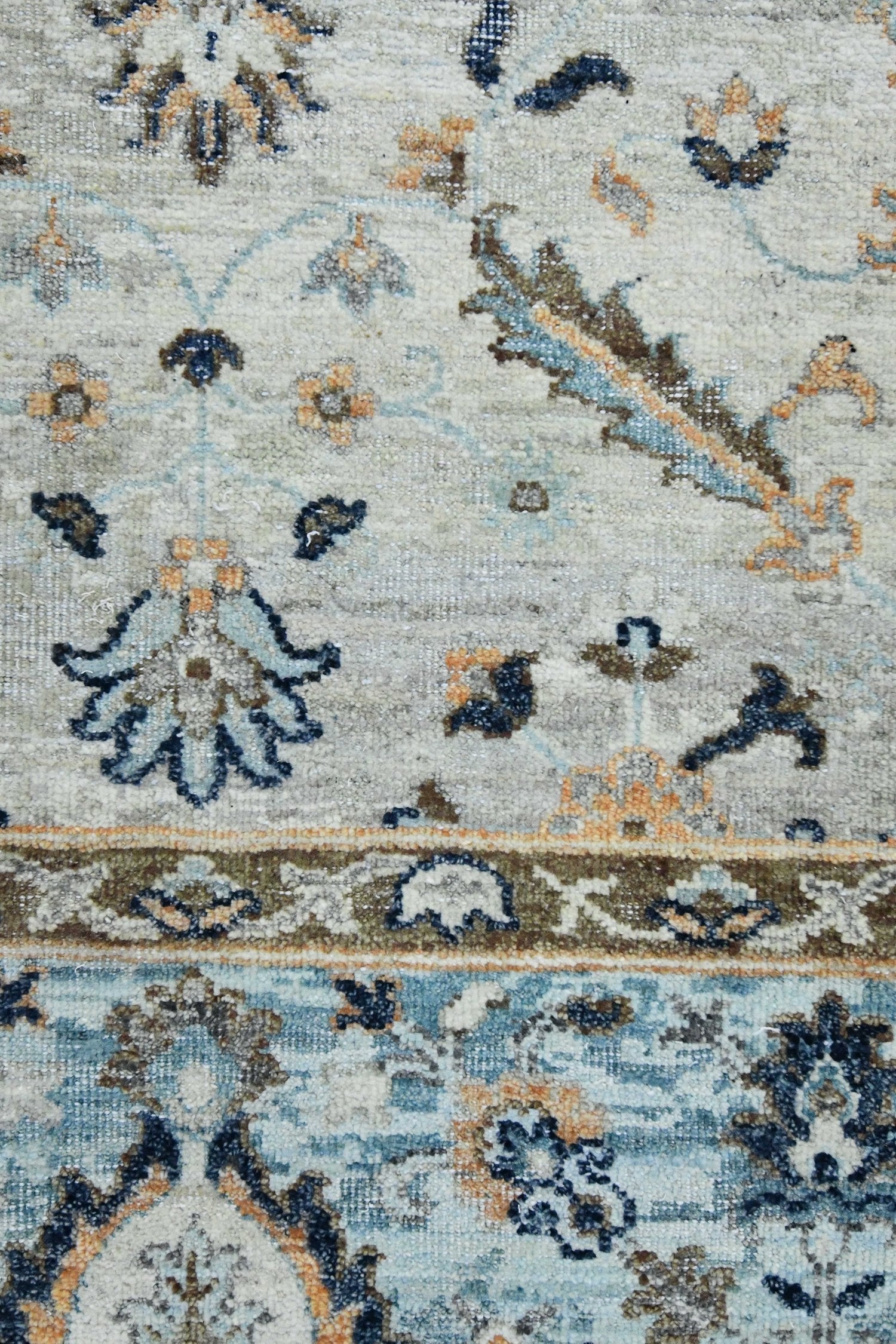 Handwoven rug detail:  Intricate floral pattern in muted blues, beige, and brown.

