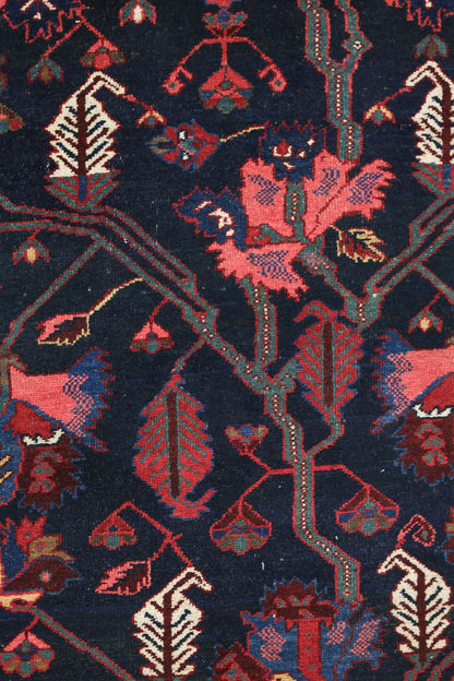 Detail of an antique Bakhtiari rug, showcasing its intricate handwoven floral pattern in deep blues and reds.
