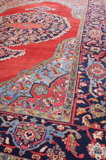 Handwoven Heriz rug detail: red, blue, and ivory floral pattern on a dark navy border.
