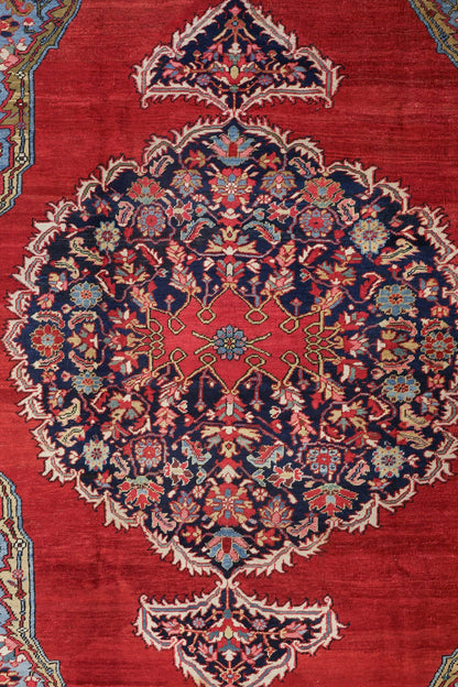 Handwoven rug detail: intricate floral medallion in navy, red, and cream on a rich red background.
