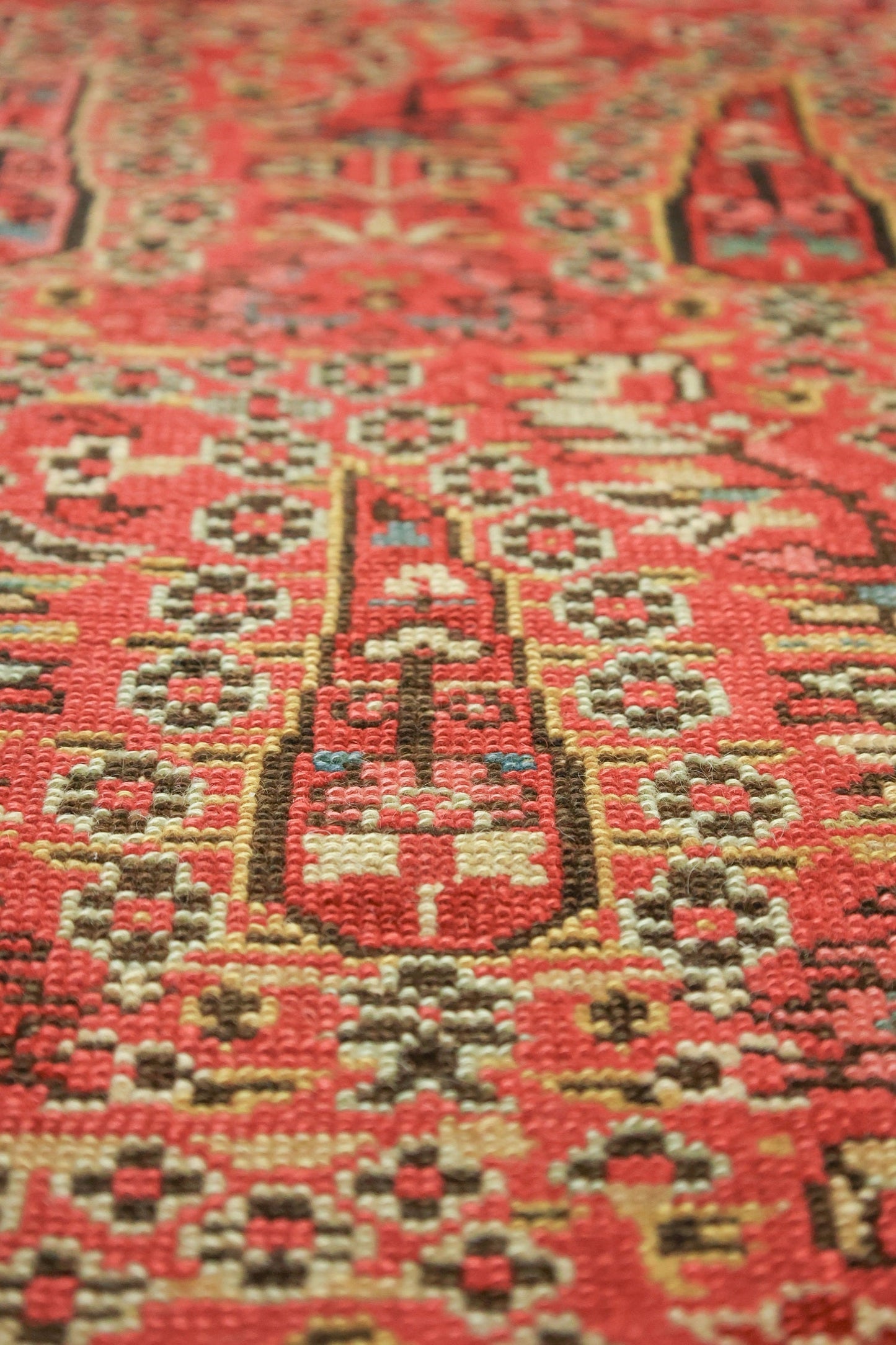 Close-up of handwoven rug's detailed, red pattern with beige and brown accents.
