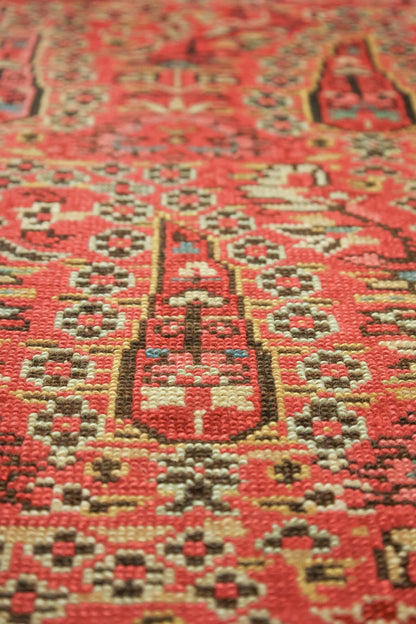 Close-up of handwoven rug's detailed, red pattern with beige and brown accents.
