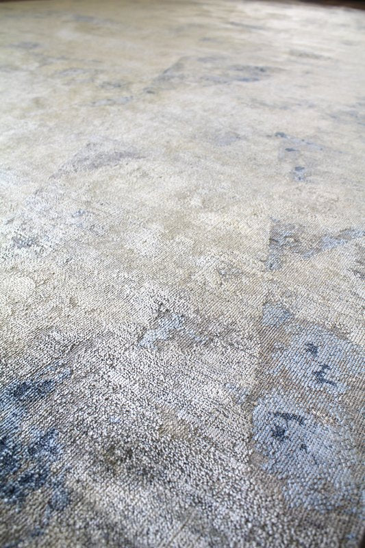 Handwoven rug detail:  Neutral tones with blue accents, textured surface.
