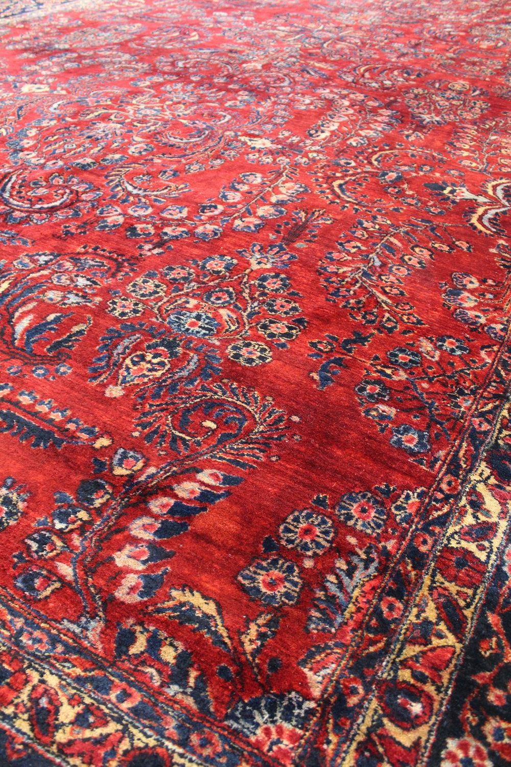 Intricate red handwoven rug detail, featuring a classic floral pattern in navy and cream.
