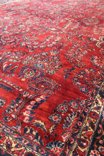 Intricate red handwoven rug detail, featuring a classic floral pattern in navy and cream.
