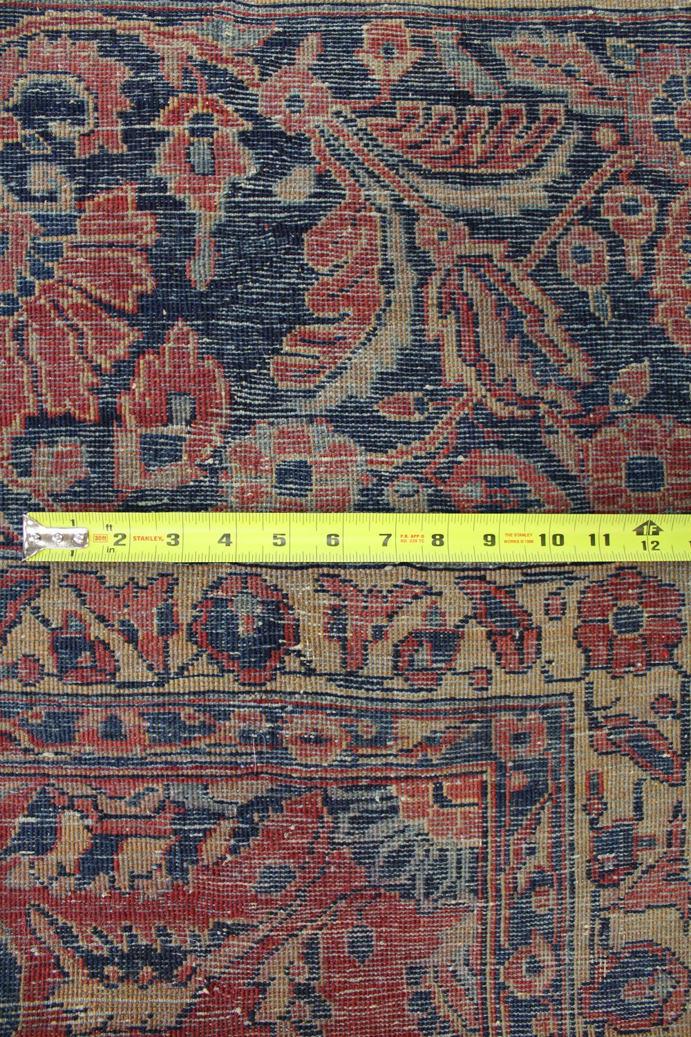 Close-up detail of antique rug's handwoven pattern, showcasing rich reds and deep blues.
