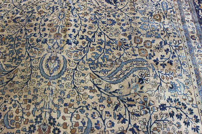 Handwoven Mashad rug detail: beige background with blue and brown floral pattern.
