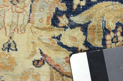 Close-up of antique rug detail, showcasing handwoven floral pattern in beige and navy.
