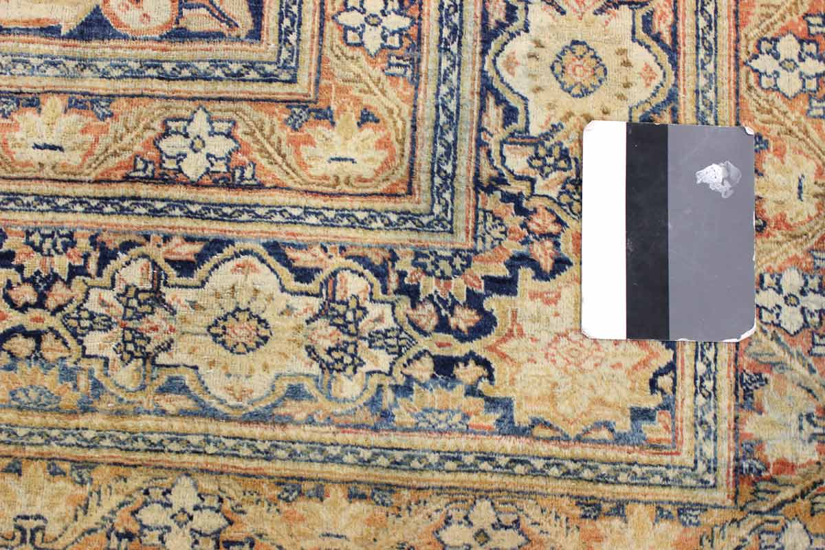 Handwoven rug detail: antique medallion pattern in beige, navy, and coral.
