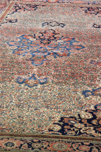 Antique handwoven rug detail, showcasing intricate floral patterns in red, blue, and cream tones.
