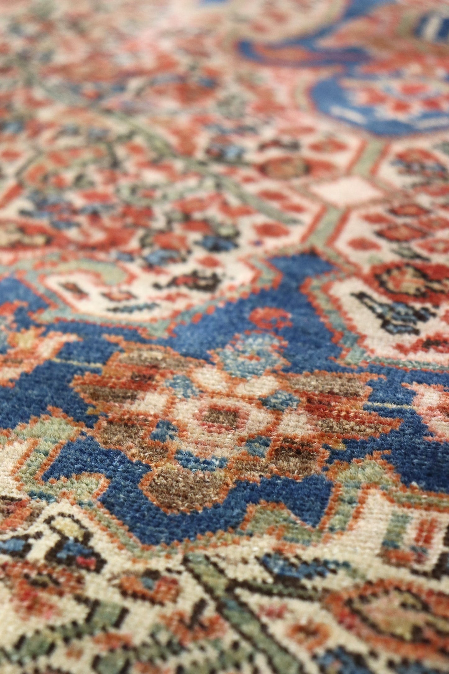 Close-up of a handwoven rug's intricate, multicolored pattern featuring blues and reds.

