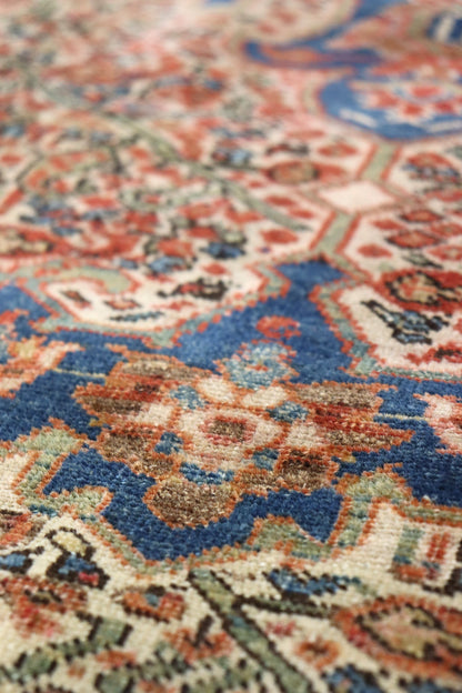 Close-up of a handwoven rug's intricate, multicolored pattern featuring blues and reds.
