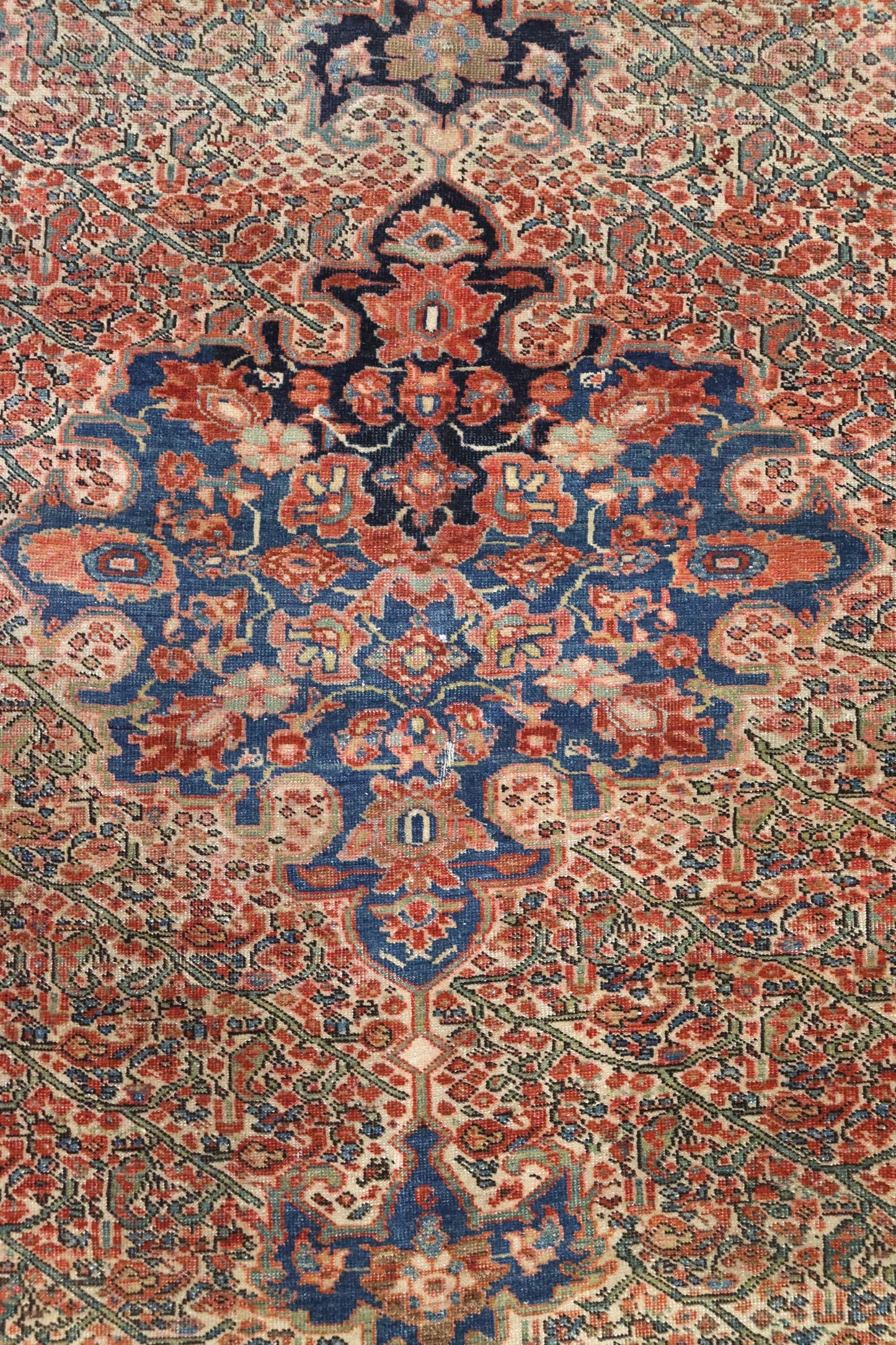 Intricate detail of antique handwoven rug in red, blue, and beige.
