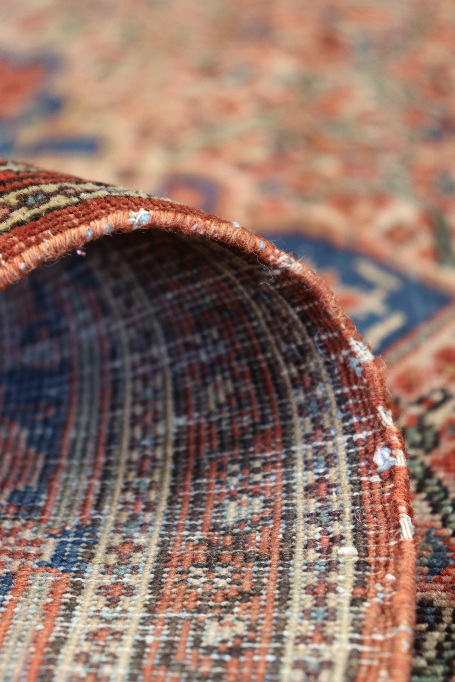 Close-up of a handwoven rug's intricate detailing, showcasing rich reds, blues, and creams in its traditional design.
