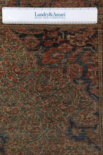 Detailed close-up of antique rug's handwoven texture, showcasing intricate red, blue, and beige patterns.

