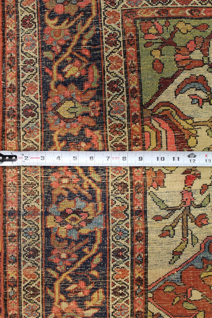 Antique Ferahan Sarouk rug detail, showcasing intricate handwoven floral patterns in muted reds, blues, and creams.
