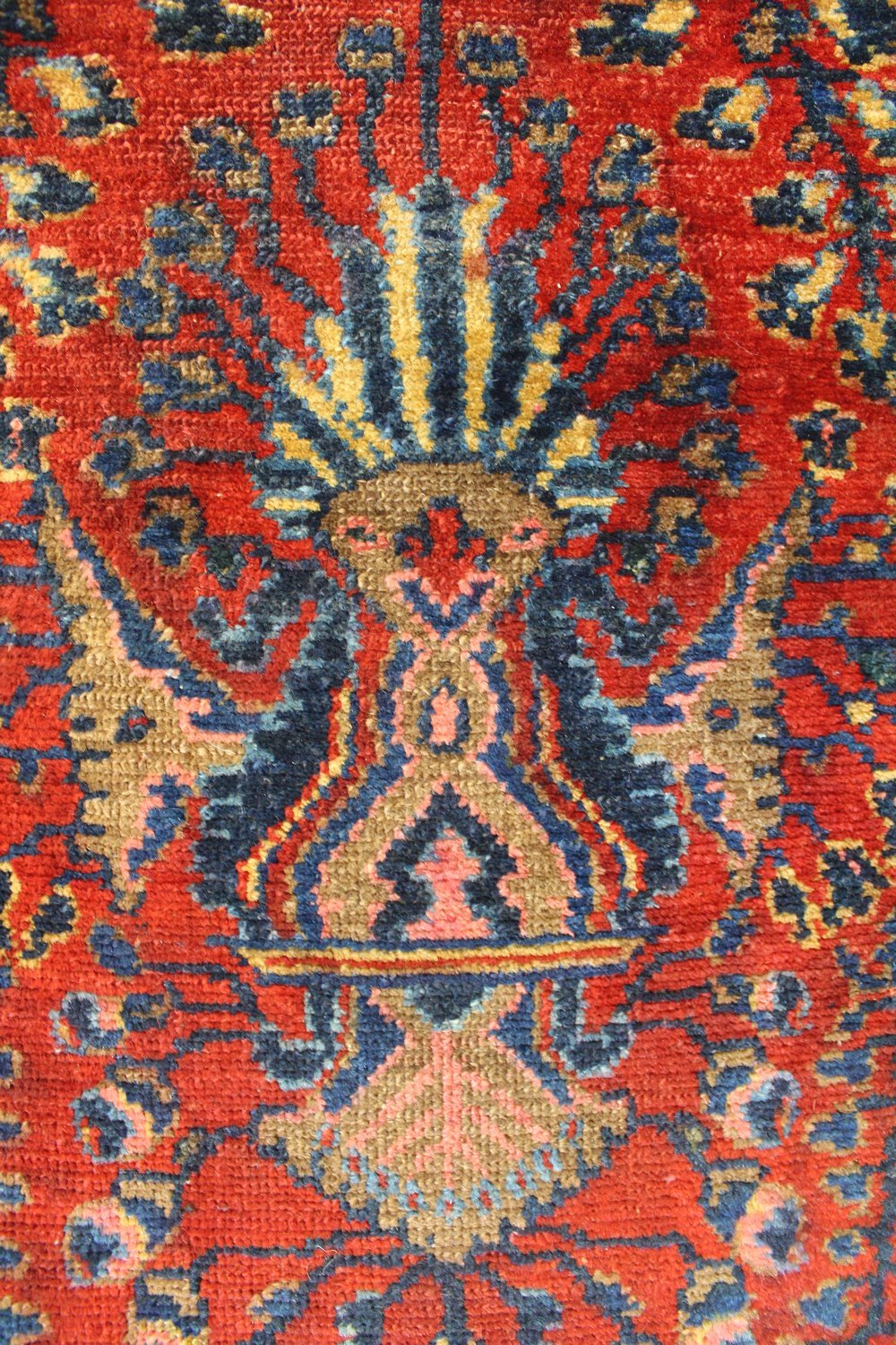 Close-up of antique rug's handwoven, red and blue pattern.
