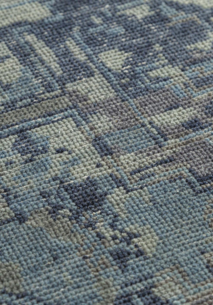Close-up of handwoven rug texture, showcasing a muted blue and gray pattern.
