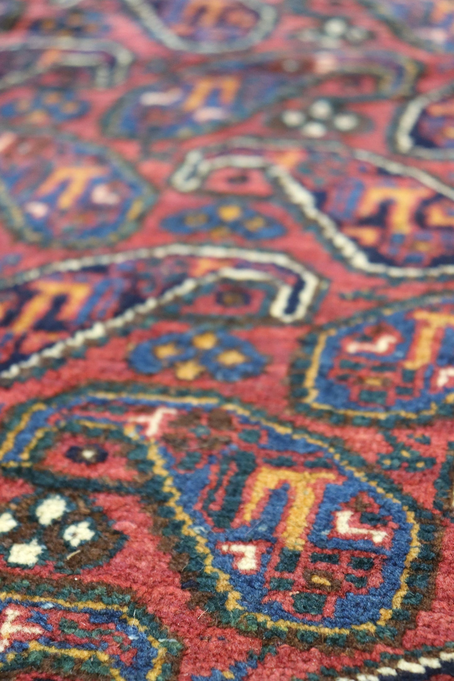 Close-up of richly colored, handwoven rug with intricate paisley pattern.
