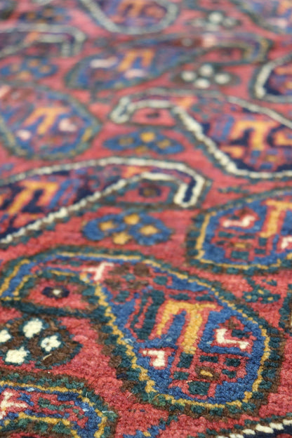 Close-up of richly colored, handwoven rug with intricate paisley pattern.
