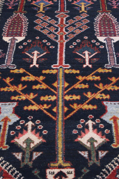 Close-up of a dark navy antique rug with intricate, colorful tribal patterns.
