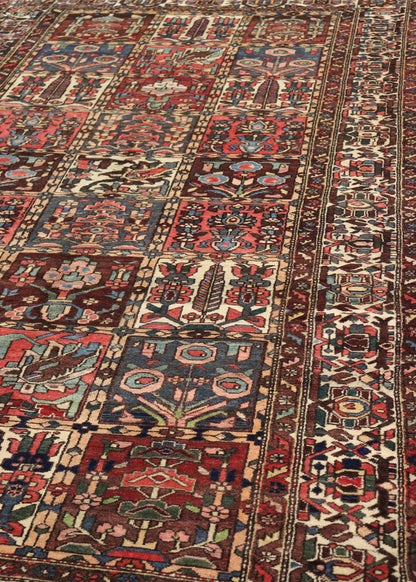 Handwoven antique rug detail, showcasing a rich tapestry of red, blue, and beige floral and geometric patterns.
