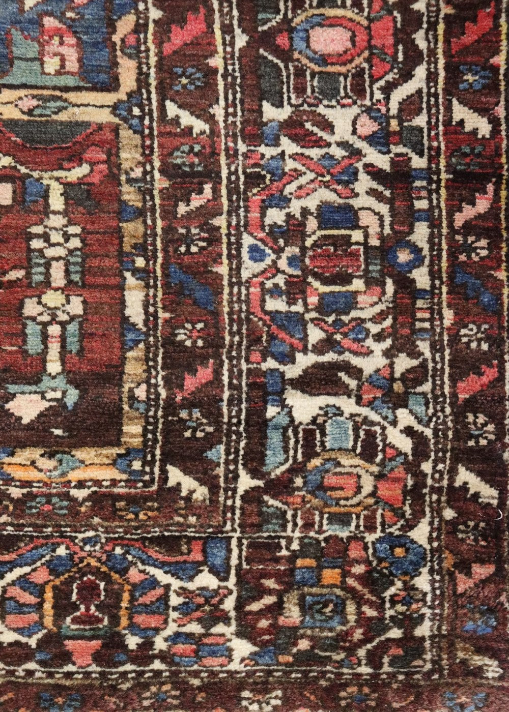 Detailed close-up of an antique rug's handwoven, multicolored pattern.

