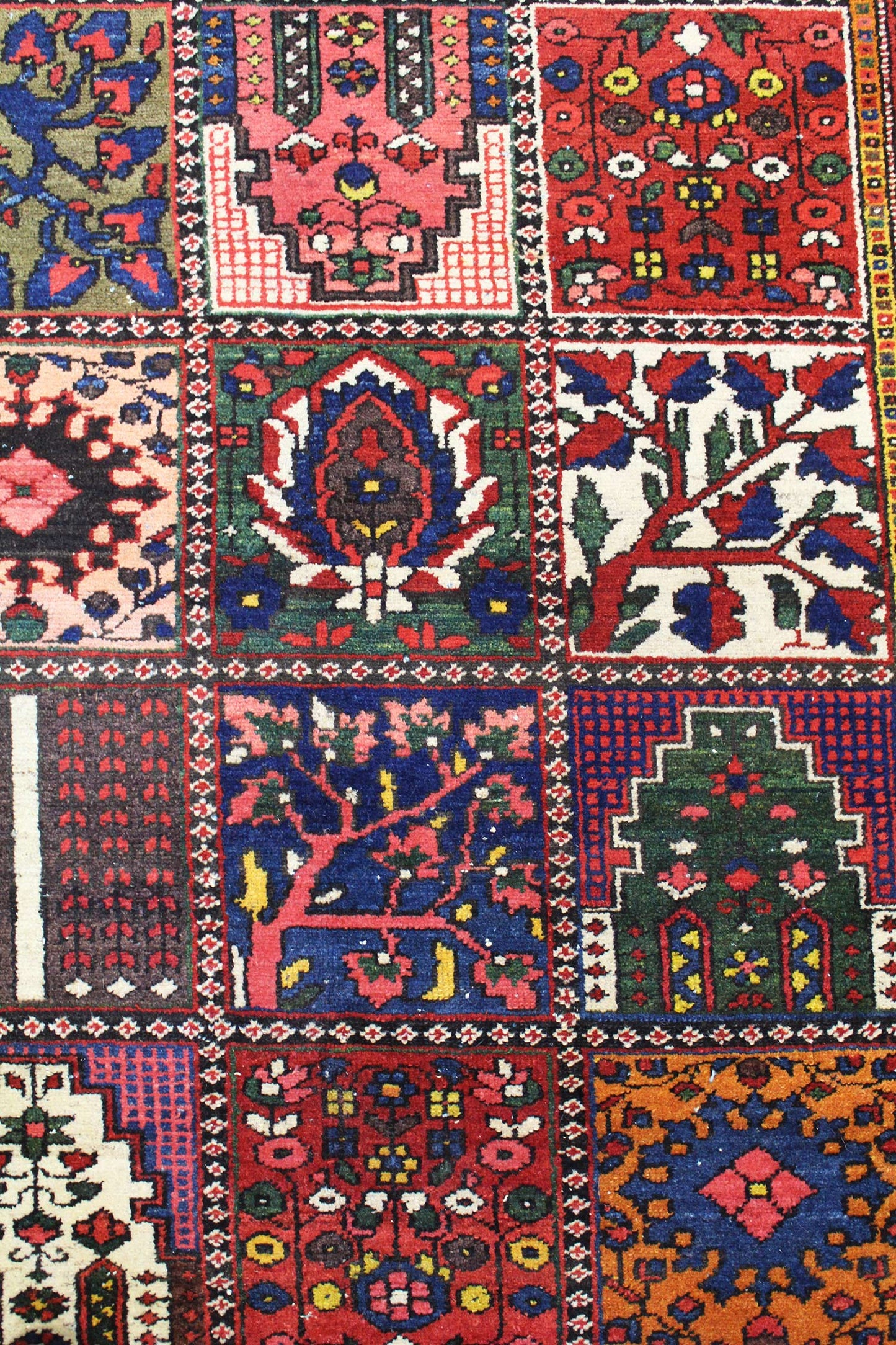 Close-up of a richly colored antique rug, showcasing intricate handwoven floral and geometric patterns.
