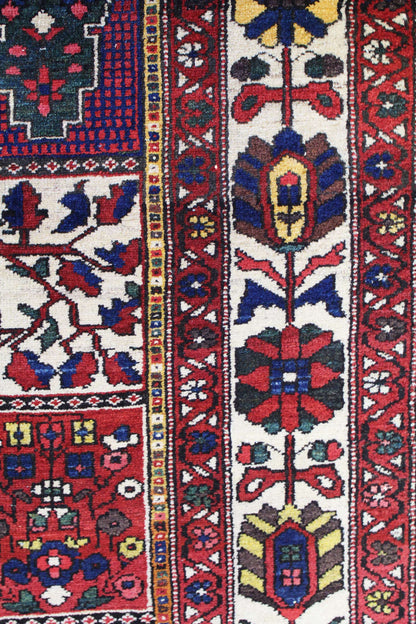 Detail of antique Bakhtiari rug, showcasing vibrant red, blue, and ivory floral patterns.
