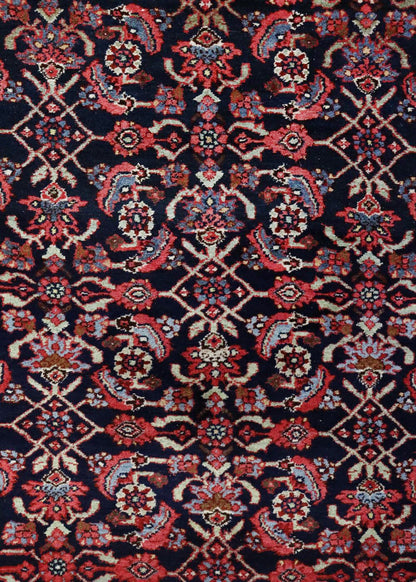 Intricate detail of a dark rug with red and blue floral patterns.
