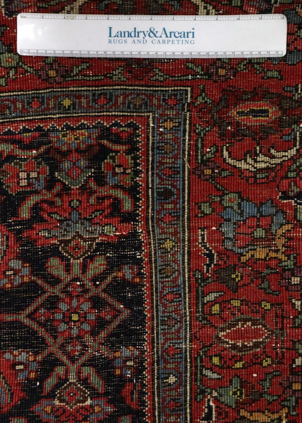 Close-up detail of an antique Bijar rug's intricate, handwoven design; rich reds and deep blues.
