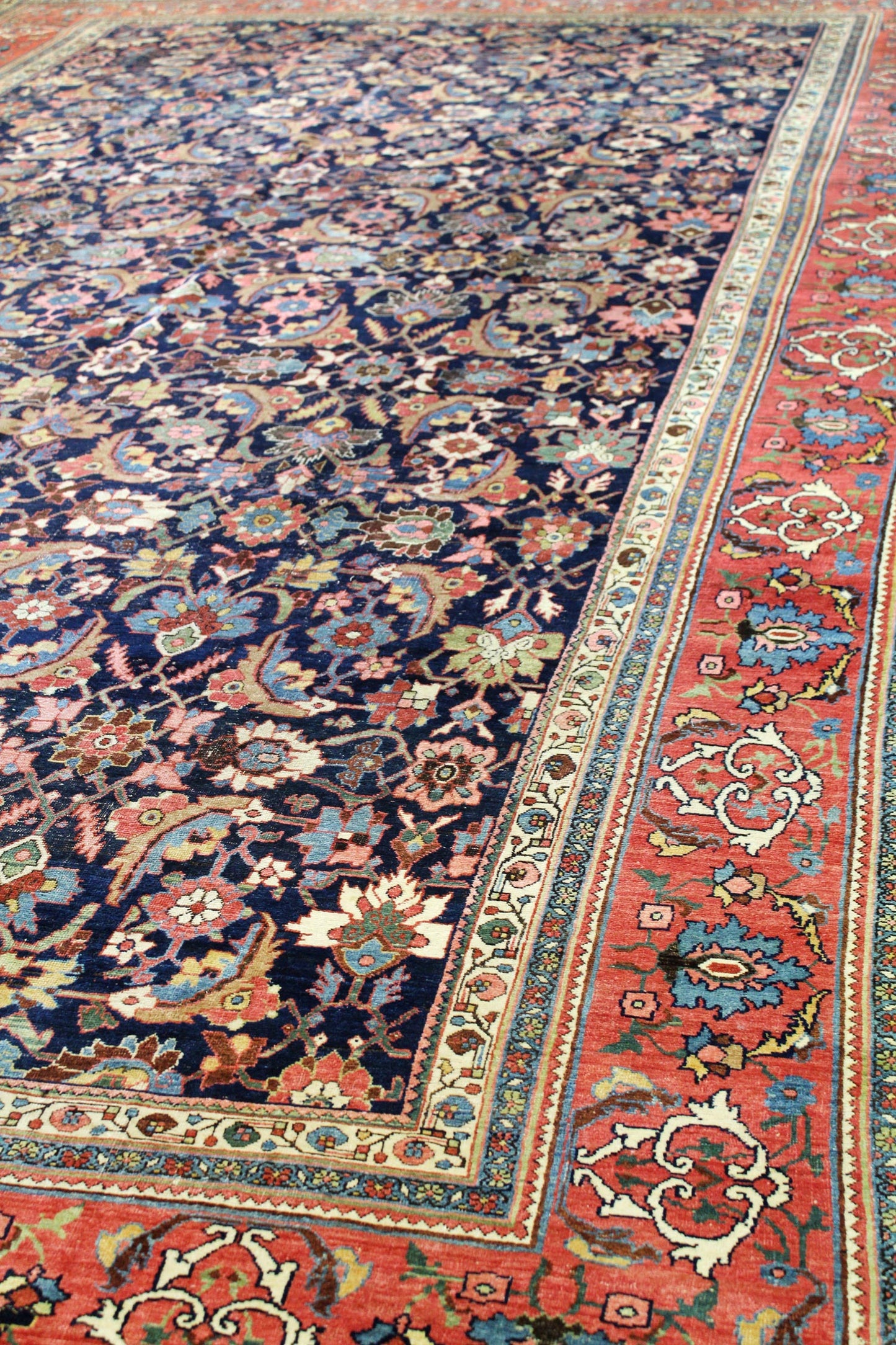 Antique Bijar rug detail: richly colored floral and arabesque patterns on a dark navy field, with a contrasting red border.
