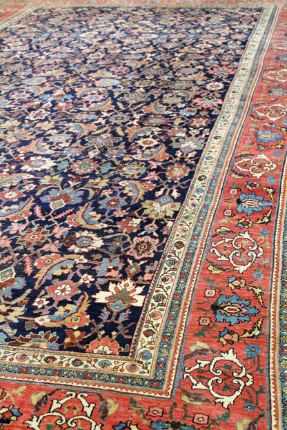 Antique Bijar rug detail: richly colored floral and arabesque patterns on a dark navy field, with a contrasting red border.
