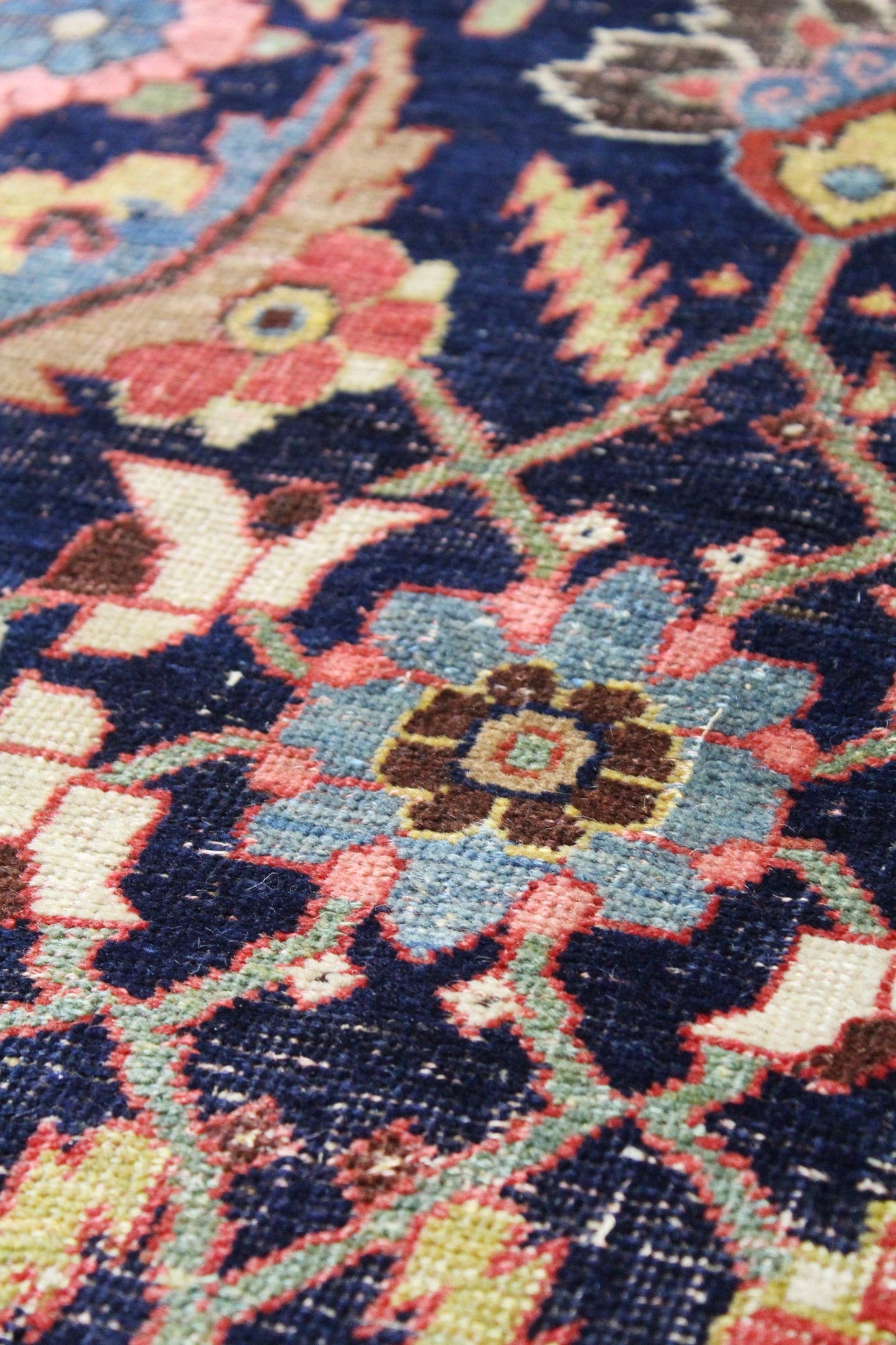 Close-up view of a richly colored antique rug with detailed floral patterns.
