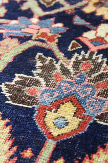 Close-up view of a handwoven rug's intricate, multicolored floral pattern.
