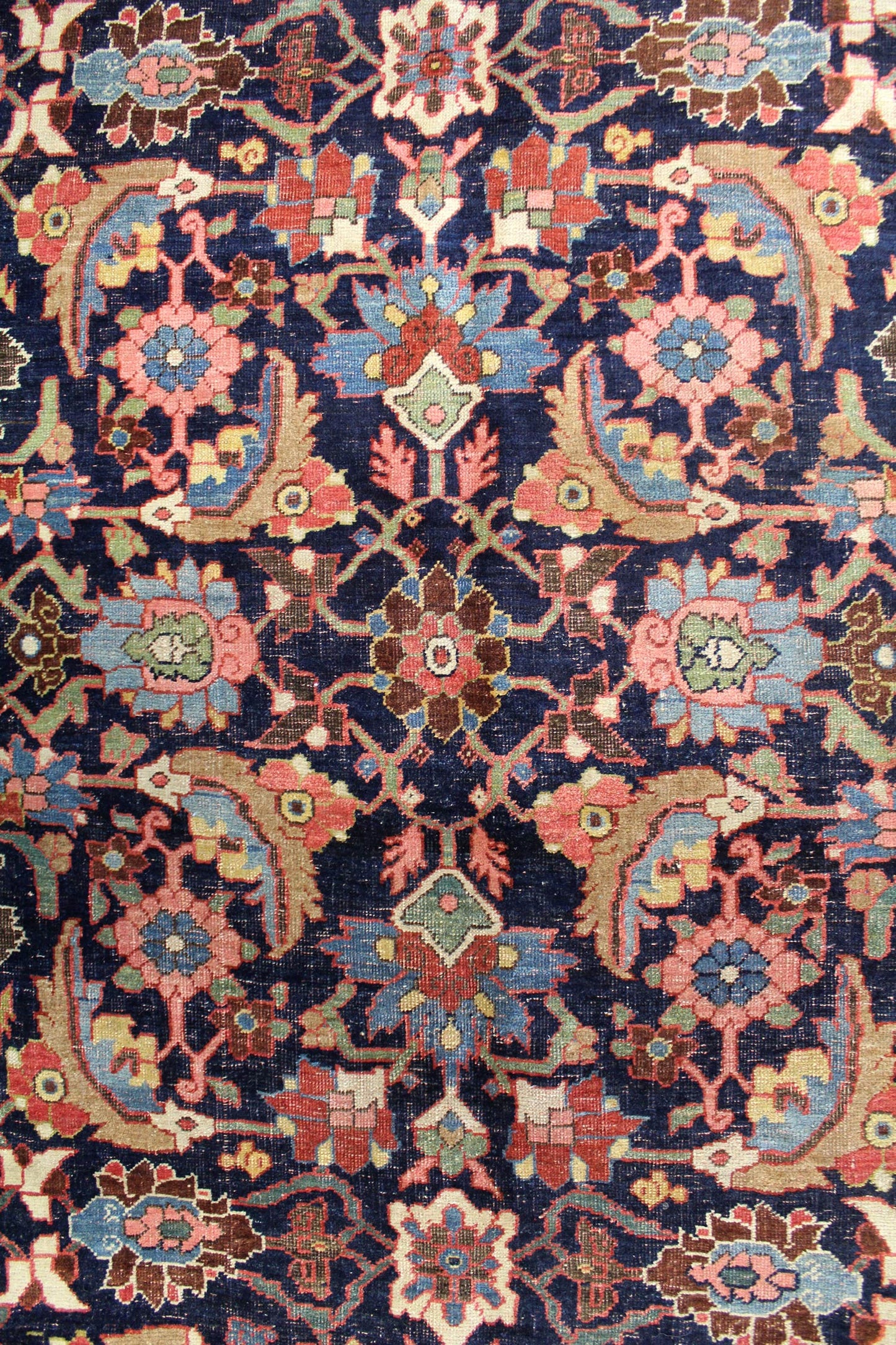Intricate detail of a vintage Bijar rug, showcasing a navy blue field with a multicolored floral pattern.
