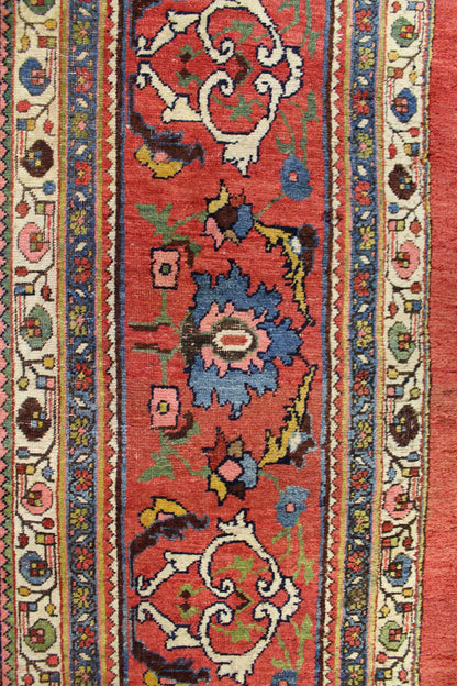 Detailed close-up of a vintage rug's red field with multicolored floral and arabesque patterns, showcasing intricate handwoven details.
