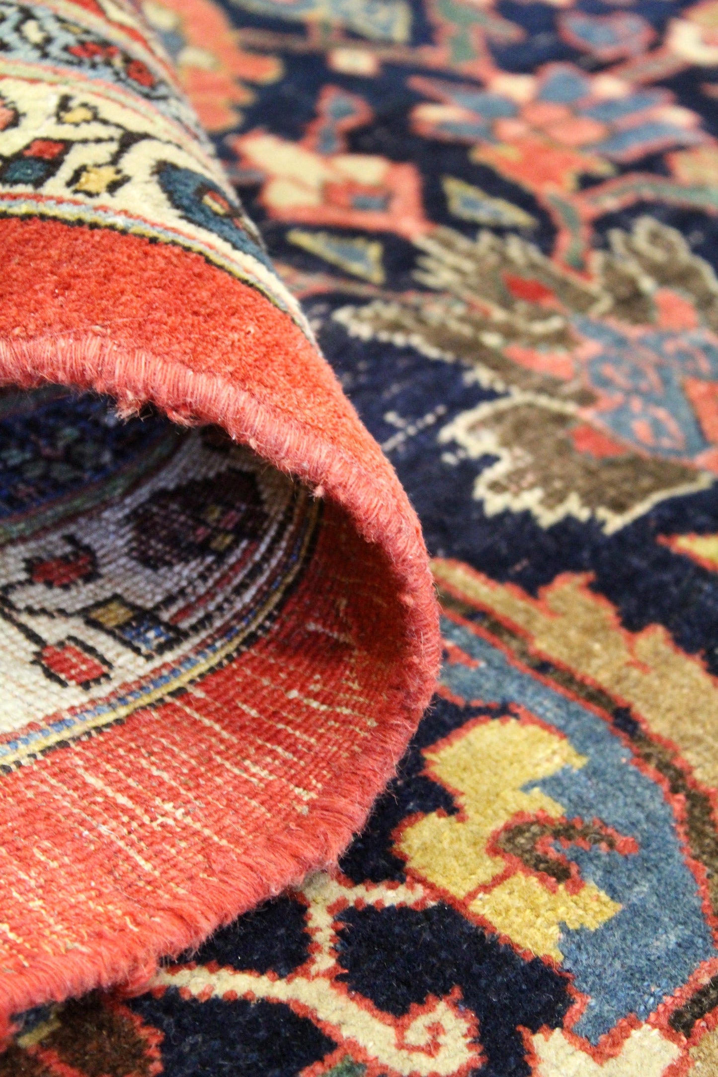 Close-up of handwoven rug's detailed border, showcasing rich reds and intricate tribal patterns.

