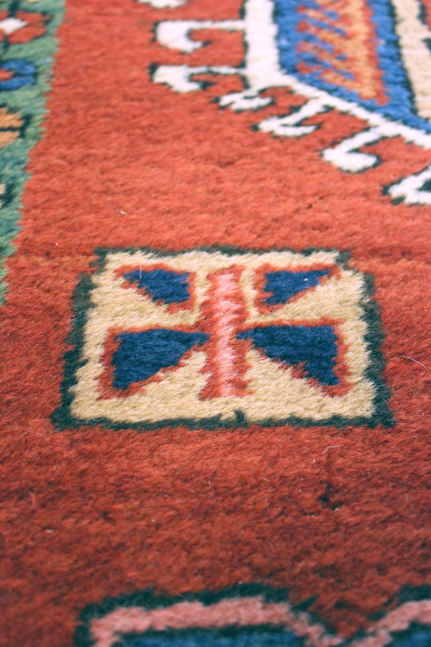 Close-up detail of a handwoven rug's intricate, multicolored design.
