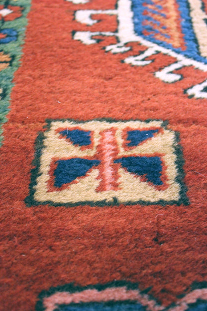 Close-up detail of a handwoven rug's intricate, multicolored design.
