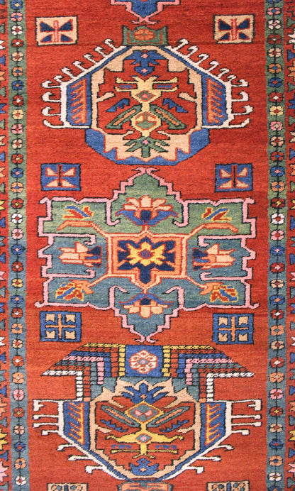 Detail of antique Heriz rug's vibrant, handwoven pattern in red, blue, and green.
