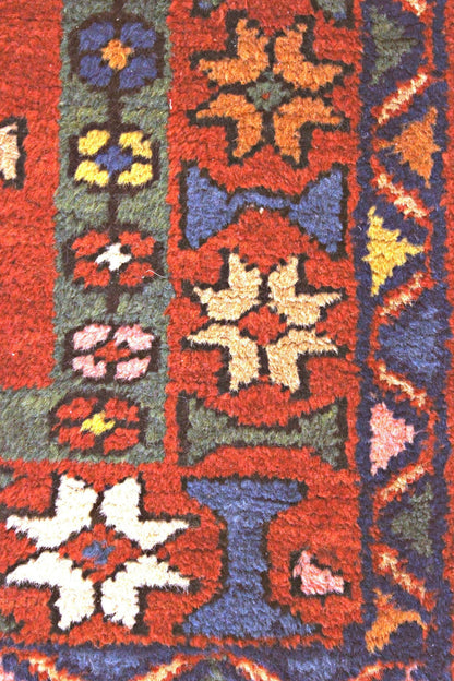 Detail of antique Heriz rug, showcasing handwoven floral pattern in red, blue, and gold tones.
