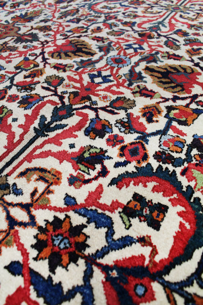 Close-up view of a handwoven rug's intricate, multicolored floral pattern on an off-white background.
