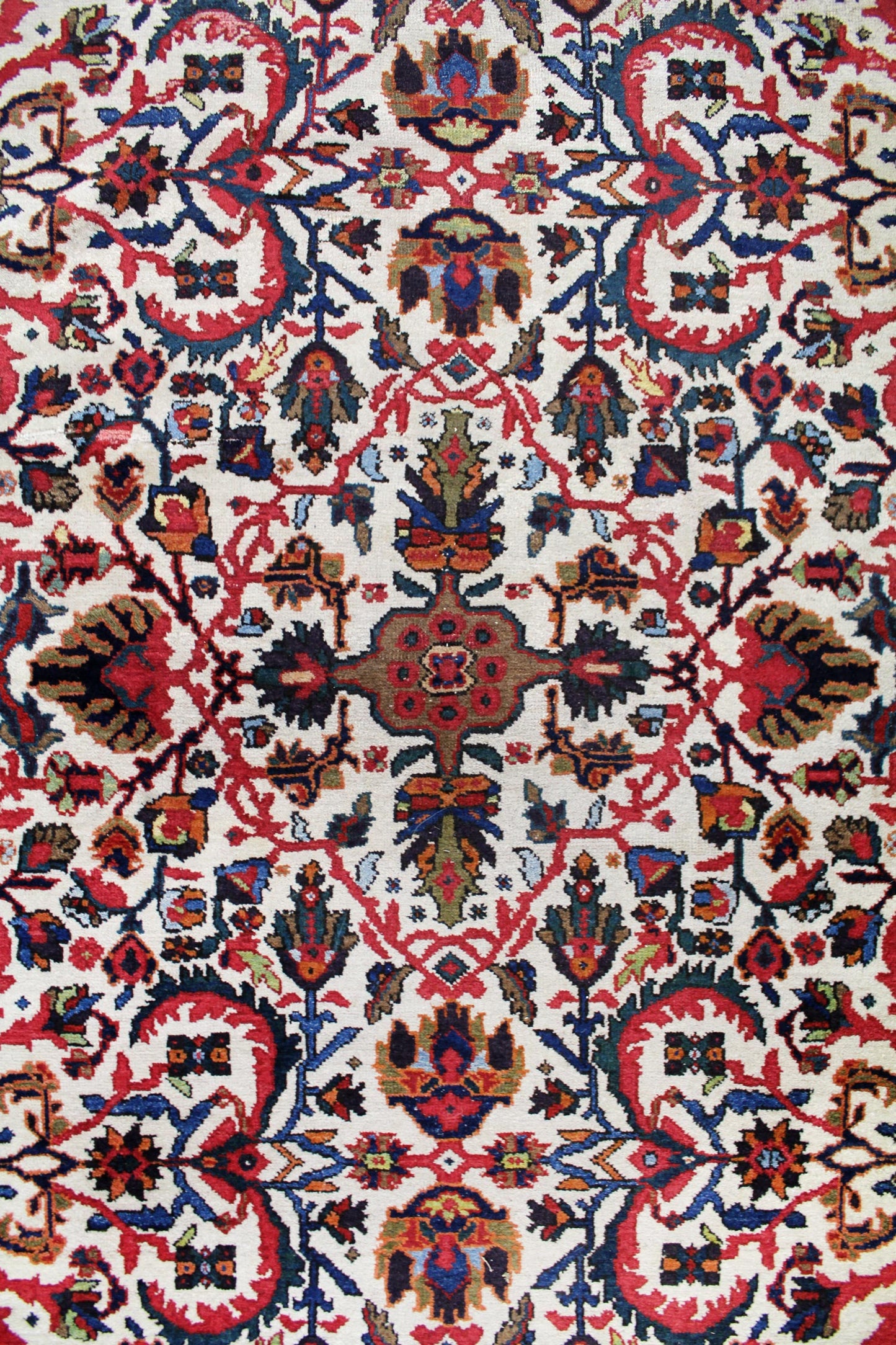 Handwoven rug detail: intricate floral pattern in red, blue, and ivory.
